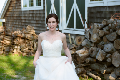 Bride walking near a barn wearing a white wedding dress.